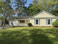 Charming single-story home boasts a manicured lawn, inviting porch and attached garage, perfect for suburban living at 317 Commons Way, Goose Creek, SC 29445