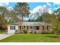 Charming one-story brick home with a well-manicured lawn and mature trees at 392 Cross St, Charleston, SC 29407