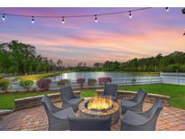 Outdoor fire pit with seating area, lake views, and string lights at dusk, perfect for relaxing and entertaining at 406 Summers Dr, Summerville, SC 29485