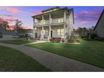 Charming two-story home with a double porch, manicured lawn, and inviting curb appeal at twilight at 4303 Misty Hollow Ln, Ravenel, SC 29470