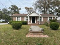 Charming brick home featuring white shutters and a cozy front porch with manicured lawn at 816 Bermuda St, Charleston, SC 29412