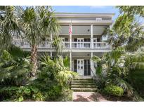 Charming two-story home with a double porch, American flag, lush landscaping and brick steps at 106 Beaufain St, Charleston, SC 29401