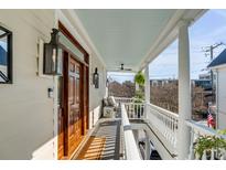 Inviting front porch featuring a wood door, pendant lighting, and a railing with an area for seating at 106 Queen St # B, Charleston, SC 29401