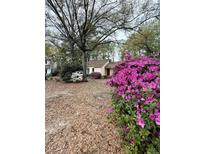 Charming home featuring a red door, surrounded by lush greenery and vibrant pink azaleas at 1291 Old Colony Rd, Mount Pleasant, SC 29464