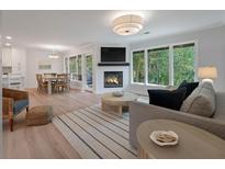Cozy living room features a fireplace, natural light, hardwood floors, and an open floor plan to the kitchen and dining room at 1330 Sea Elder Dr # C, Kiawah Island, SC 29455