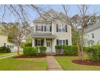 Charming two-story home featuring a well-manicured lawn, and a welcoming front porch framed by lush greenery at 1833 Hubbell Dr, Mount Pleasant, SC 29466