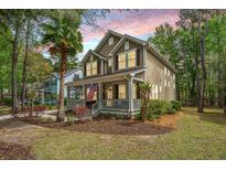 Charming two-story home with a welcoming front porch, American flag, palm tree, and a well-manicured lawn at 1883 Hall Point Rd, Mount Pleasant, SC 29466