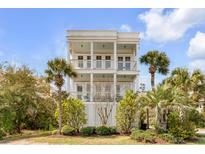 Charming three-story home featuring double balconies and well-manicured landscaping with palm trees at 904 Middle St, Sullivans Island, SC 29482