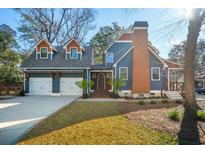 Charming blue home showcasing a two-car garage, front door, manicured lawn and blue skies at 1056 Wharf Indigo Pl, Mount Pleasant, SC 29464
