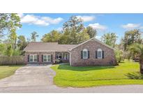 Charming brick home with manicured lawn, mature trees, and a welcoming driveway on a sunny day at 1342 Dennis Blvd, Moncks Corner, SC 29461