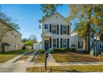 Charming two-story home featuring classic black shutters, a well-manicured lawn, and a convenient detached garage at 137 St Phillips Row, Summerville, SC 29485