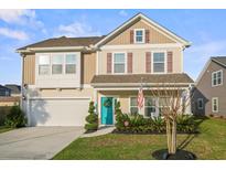 Charming two-story home boasts a well-manicured lawn, turquoise door and attached garage, offering curb appeal at 1529 Fishbone Dr, Johns Island, SC 29455