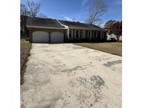Charming single story brick home featuring an attached two car garage and large concrete driveway at 1561 Montclair St, Charleston, SC 29407