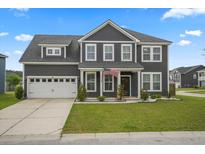 Charming two-story home boasts a well-manicured lawn, attached garage, and welcoming front porch with an American flag at 180 Basket Grass Ln, Summerville, SC 29486