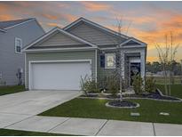 Charming single-Gathering home features manicured lawn, two car garage and craftsman style architecture at sunset at 215 Sweet Cherry Ln, Summerville, SC 29486