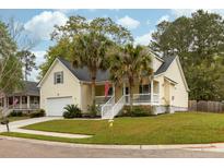 Charming yellow two-story home with front porch, palm trees, and well-manicured lawn at 225 Hanahan Plantation Cir, Hanahan, SC 29410