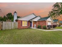 Charming single-story brick home featuring a well-manicured lawn and cozy front porch at sunset at 234 Two Hitch Rd, Goose Creek, SC 29445