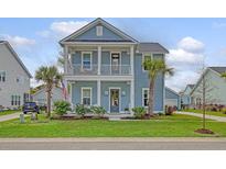 Charming two-story home with a light blue exterior, double porches, and lush landscaping at 2383 Lenwick Hall Ln, Johns Island, SC 29455