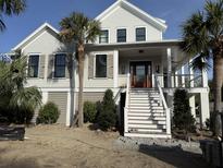Charming two-story home with a welcoming front porch, palm trees, and beautiful architectural details at 2870 Ion Ave, Sullivans Island, SC 29482