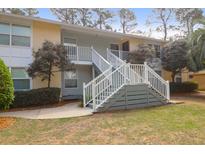 Two-story condo featuring stair access, landscaping, and mature trees on a sunny day at 341 W Coleman Blvd # F, Mount Pleasant, SC 29464