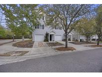 Charming townhome featuring light gray siding, a one-car garage, and a well-manicured lawn with mature trees at 4120 Veritas St, Charleston, SC 29414