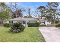 Charming single-story home features a landscaped yard, long driveway, and a brick chimney at 734 W Oak Forest Dr, Charleston, SC 29407