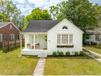 Charming white brick home featuring a covered porch with seating and a well-manicured front yard at 85 Colleton Dr, Charleston, SC 29407