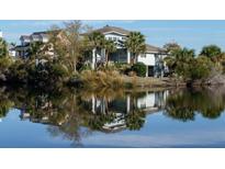 Stunning waterfront home reflecting on the lake, surrounded by lush greenery and palm trees at 1 Battery Park Rd, Edisto Island, SC 29438