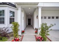 Inviting front entrance featuring a covered porch, white columns, and meticulously arranged potted flowers at 280 Swamp Creek Ln, Moncks Corner, SC 29461
