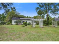 Charming single story home with white siding, green trim, solar panels, and landscaped yard with a white pergola at 3378 Von Ohsen Rd, Ladson, SC 29485