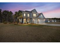 Two-story home featuring a manicured lawn, three-car garage and beautiful architectural details at 547 Pontoon Rd, Huger, SC 29450