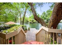 Wooden dock extends into a serene lake surrounded by lush greenery, as seen from an elevated wooden deck at 753 Lake Frances Dr, Charleston, SC 29412