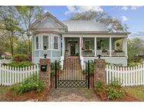 Charming light blue two-story home with a landscaped yard, brick gate posts, and a quaint white picket fence at 803 S Main St, Summerville, SC 29483