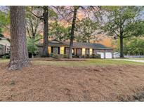 Charming brick home featuring an attached two-car garage and a welcoming front yard surrounded by mature trees at 811 E Estates Blvd, Charleston, SC 29414