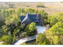 Aerial view of a wooded estate featuring a charming home and a marsh in the background at 83 Blue Heron Pond Rd, Kiawah Island, SC 29455