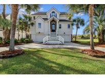 Charming two-story home with a well-manicured lawn, palm trees, and an inviting entrance at 9 Intracoastal Ct, Isle of Palms, SC 29451