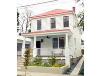 Charming two-story home featuring a red metal roof, welcoming front porch, and beautiful flower beds at 10 Killians St, Charleston, SC 29403