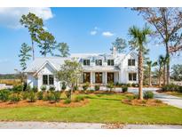 Beautiful white home with a metal roof and professionally landscaped front yard and mature trees at 116 Peninsula Dr, Ravenel, SC 29470