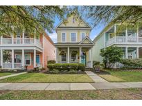 Charming yellow two-story home with a welcoming front porch and beautifully landscaped front yard at 123 Hyacinth St, Summerville, SC 29483