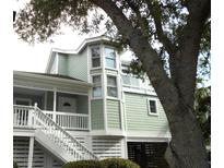 Charming coastal home with a light green exterior, white trim and a unique bay window feature at 2 Pelican Reach # Share 11, Isle of Palms, SC 29451