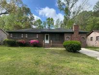 Charming brick home featuring a well-maintained front yard with blooming bushes and classic architectural details at 3143 Bonanza Rd, Charleston, SC 29414