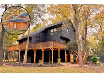 Stunning dark home exterior with a large wraparound deck and complementing natural wood staircase at 6464 St Anthony Dr, Hollywood, SC 29449