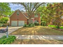 Charming two-story brick home with a well-manicured lawn, mature trees, and a two-car garage at 1026 Stono River Dr, Charleston, SC 29412