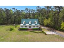 Charming home with a green metal roof, white siding, and a beautifully landscaped front yard surrounded by lush trees at 1694 Jedburg Rd, Summerville, SC 29486