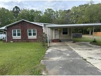 A charming single-story home with a brick facade and a convenient covered carport, surrounded by a green lawn and trees at 233 N Pandora Dr, Goose Creek, SC 29445