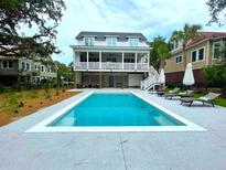 Bright in-ground pool with surrounding lounge chairs, umbrellas, and a two-story home in the background at 3510 Myrtle St, Edisto Island, SC 29438
