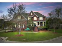 Charming two-story brick home with manicured lawn and inviting front porch with rocking chairs at 3584 Somerset Hills Ct, Mount Pleasant, SC 29466