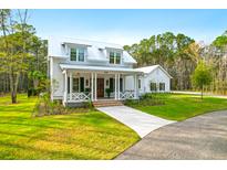 Charming two-story home with a metal roof, inviting front porch, and lush landscaping at 4310 Stonehouse Cir, Awendaw, SC 29429