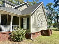 Charming home exterior with a brick foundation, siding, well-maintained landscaping, and a welcoming porch at 5182 Forest Oaks Dr, Hollywood, SC 29449