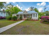 Charming home with a metal roof, inviting front porch with rocking chairs, and lush landscaping at 617 Hampton St, Walterboro, SC 29488